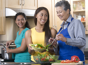 Three women in kitchen making a meal.