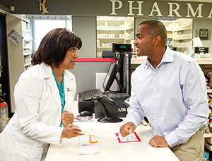 Pharmacist talking to man at pharmacy counter.