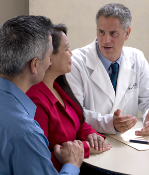 Hombre y mujer sentados y conversando con un proveedor de atención médica.