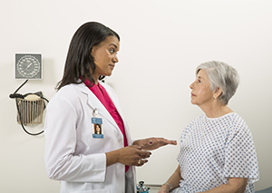 Mujer sentada en una camilla, hablando con un médico.